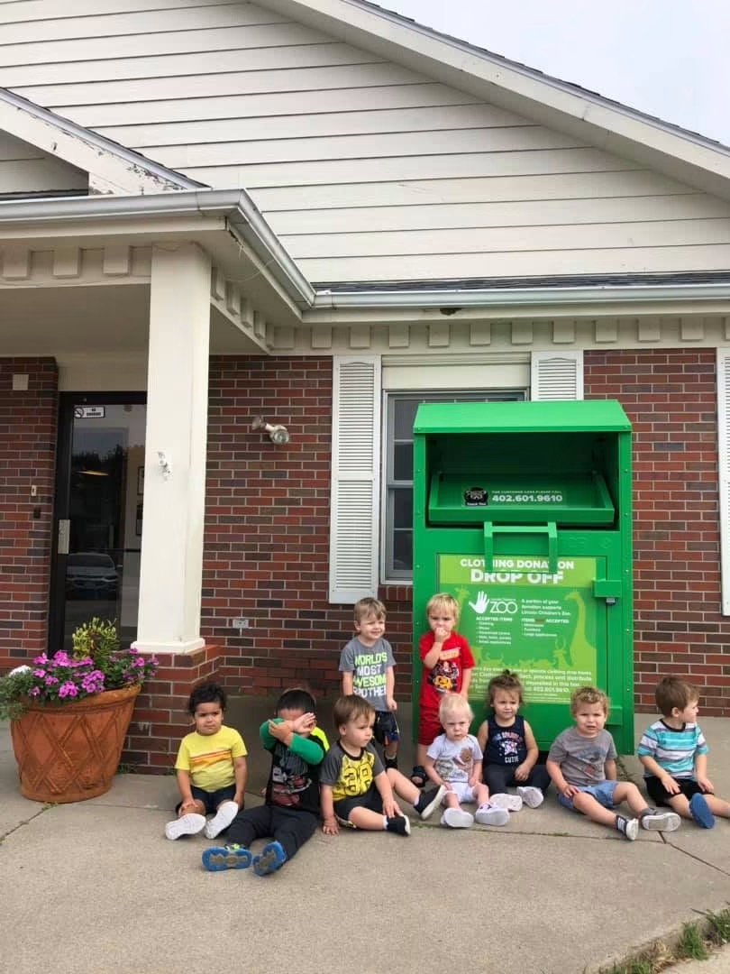 Children sitting in front of a Green Machine donation bin