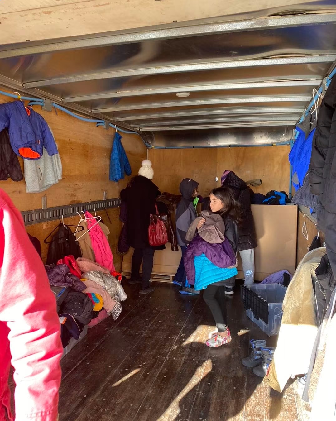 Neighbors picking out warm coats from inside the donation truck